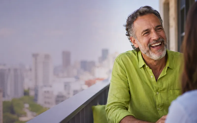 Man laughing on a balcony wearing a lime green shirt