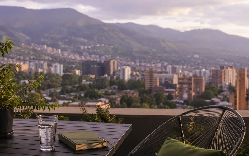 Medellin skyline at golden hour from a terrace with a glass of water and a notebook